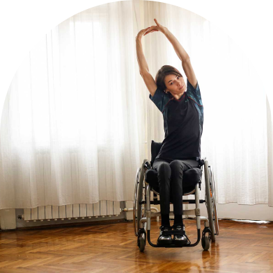 Woman in wheelchair stretching both arms above her head.