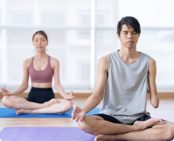 Two adults a man who had a hand amputation and a woman at the back doing a yoga pose.